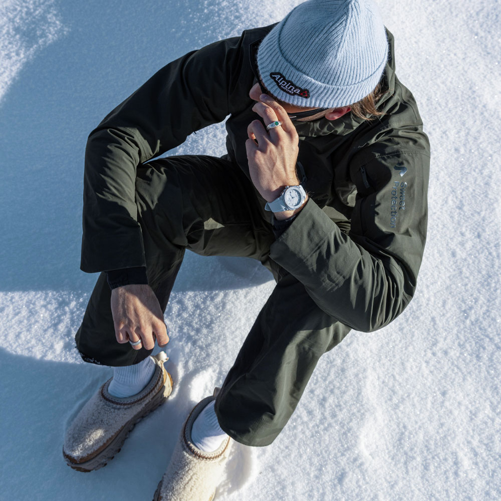 Männliches Model sitzt im Schnee und trägt die Alpiner Extreme Solarmetre von Alpina