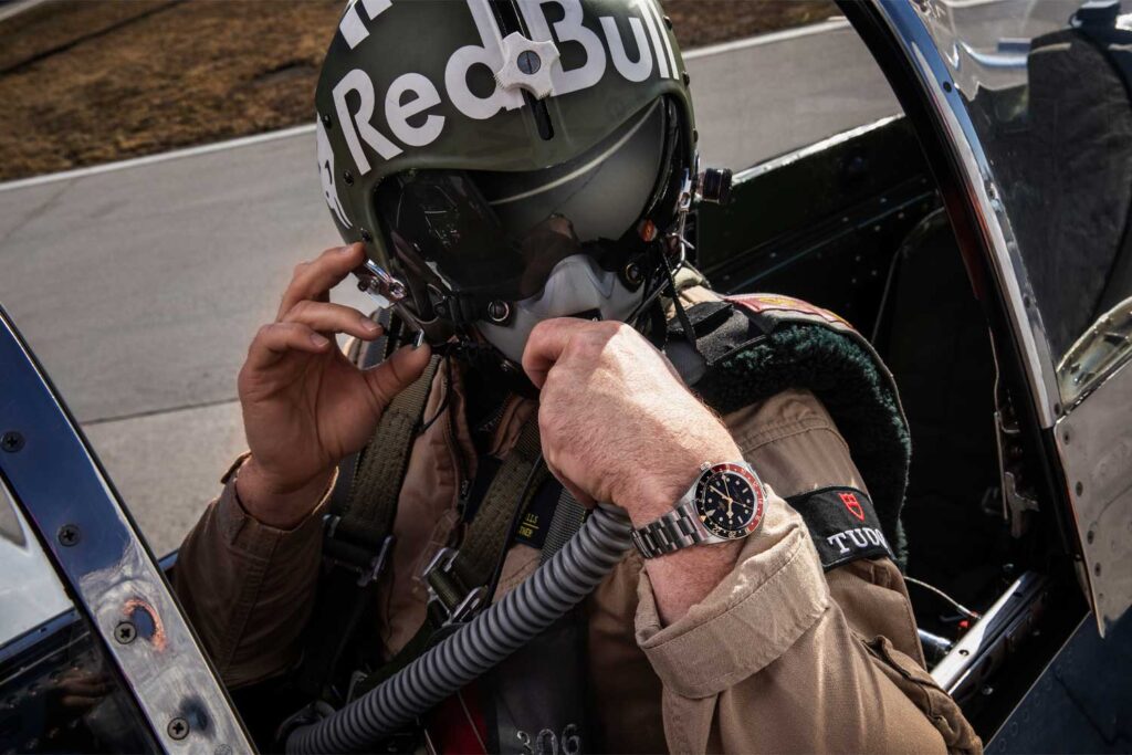 Ein Pilot mit Helm von Red Bull trägt eine Tudor