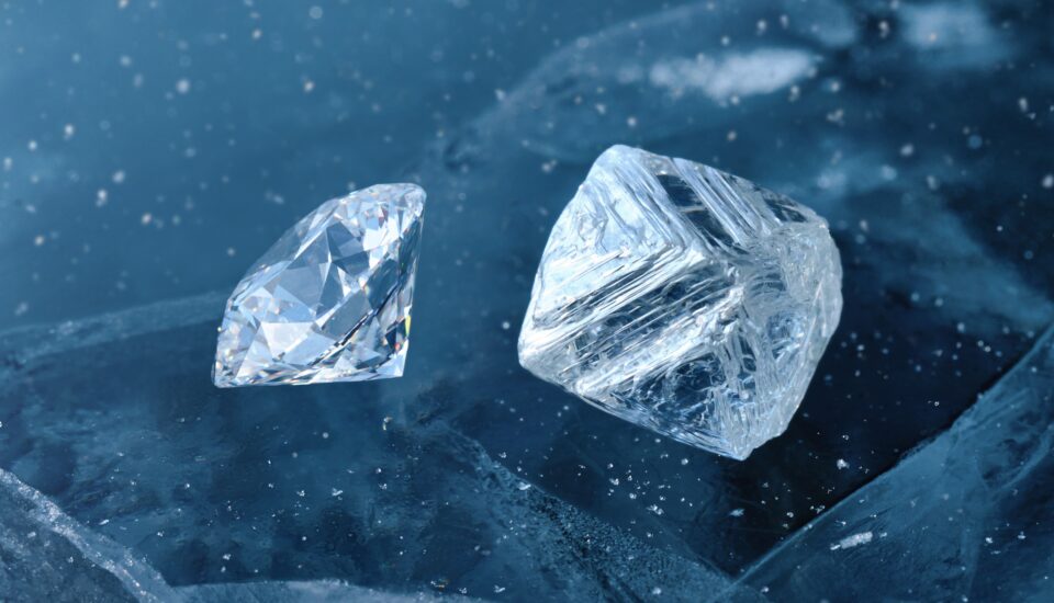 Ein geschliffener Diamant und ein ungeschliffener Rohdiamant unter Wasser umgeben von Eisschollen.