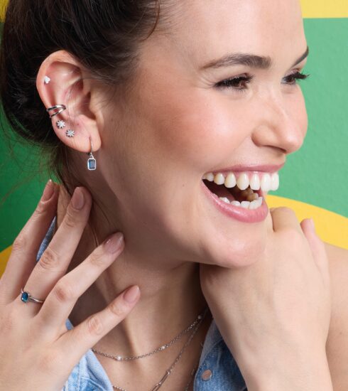 Lachende Frau vor grünem Hintergrund mit Trendschmuck von Leonardo Ciao.