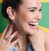 Lachende Frau vor grünem Hintergrund mit Trendschmuck von Leonardo Ciao.