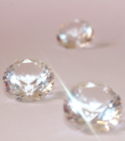 Drei Diamanten im Brillantschliff auf rosa Hintergrund.