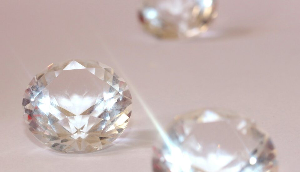 Drei Diamanten im Brillantschliff auf rosa Hintergrund.