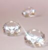 Drei Diamanten im Brillantschliff auf rosa Hintergrund.