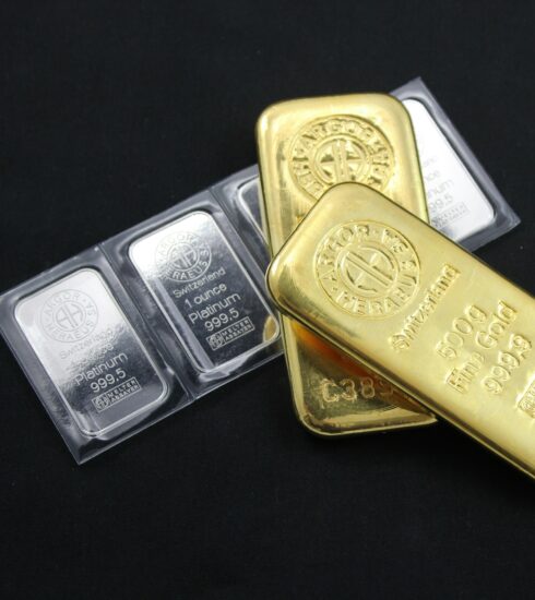 Platinbarren und Goldbarren vor schwartem Hintergrund.