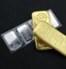 Platinbarren und Goldbarren vor schwartem Hintergrund.