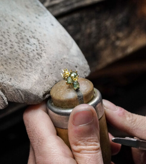 A goldsmith's hands are working on a piece of jewelry by Brusi.