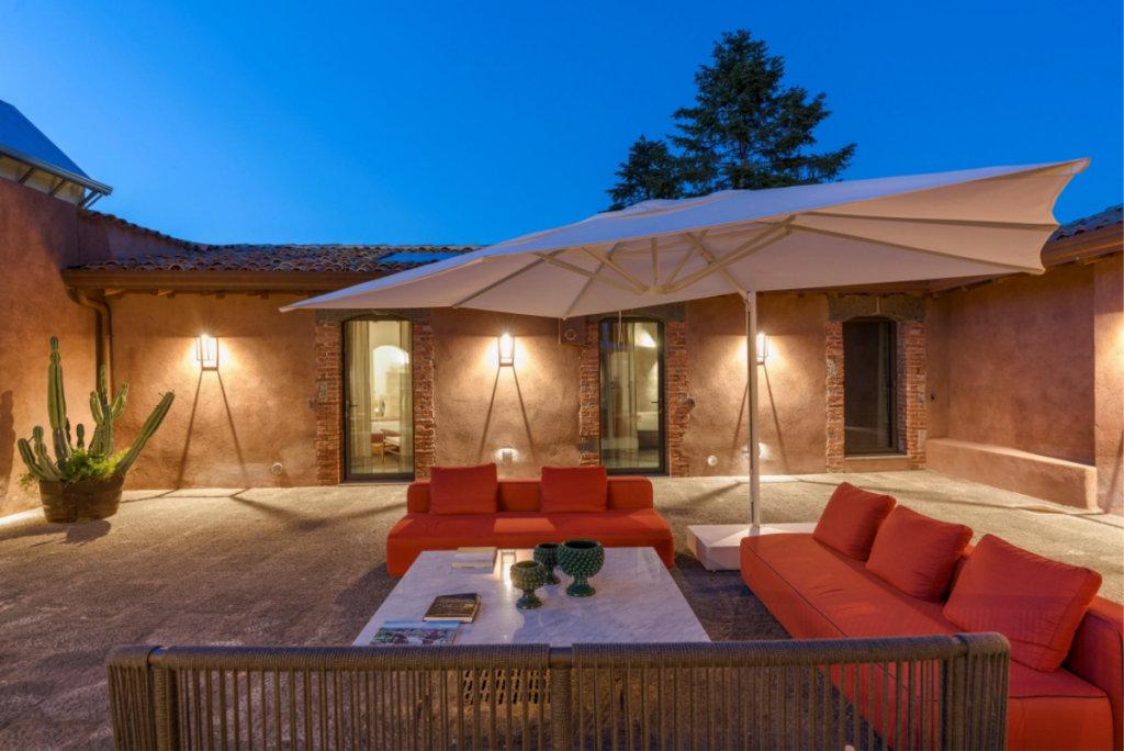Dimora Cottanera courtyard in the evening with seating and umbrellas - evening atmosphere
