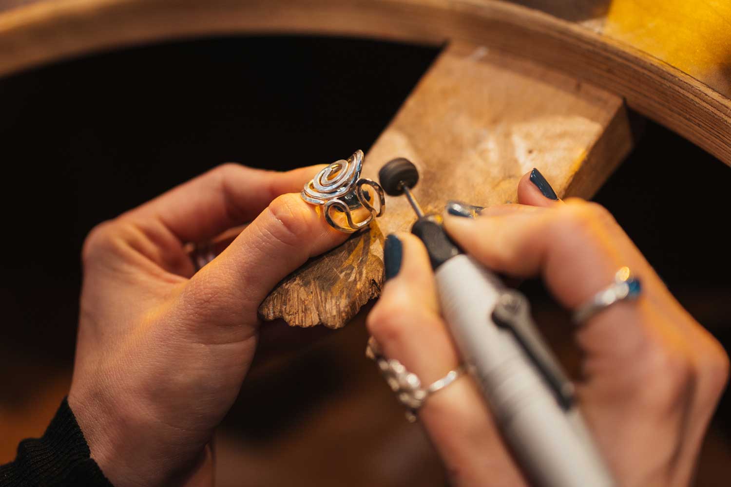 Two goldsmith hands are working on a ring.