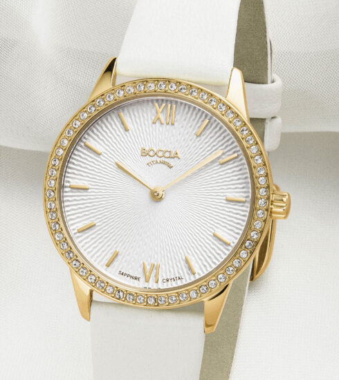 Uhr von Boccia Titanium mit weißem Zifferblatt, Kristalsteinen auf der Lünette, goldplattiertem Titan-Gehäuse und weißem Armband.