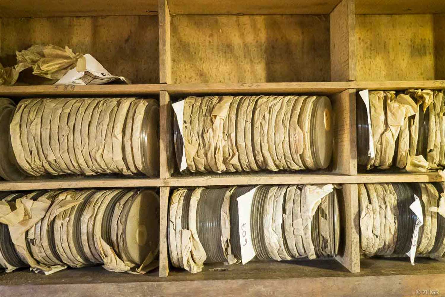 Blick in ein Regal mit in Papier eingewickelten Uhrengläsern