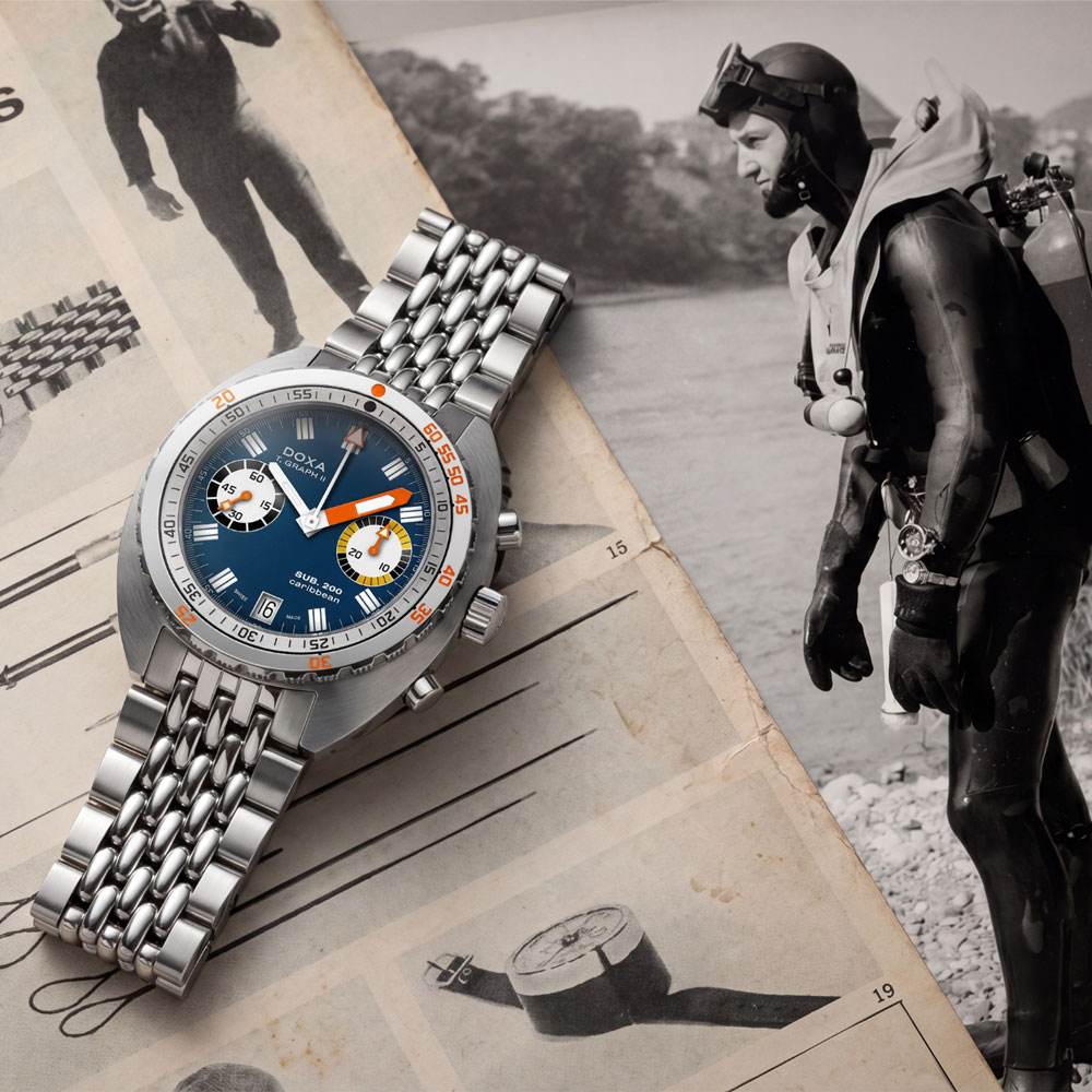 Doxa SUB 200 TGRAPH-II vor einem historischen Katalog-/Zeitungsmotiv mit Taucher