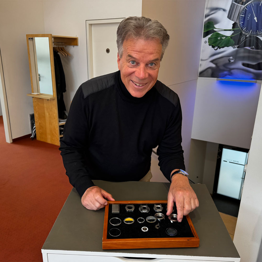 Klaus Botta in seinem Atelier mit einem Kasten mit Komponenten seiner Uhren