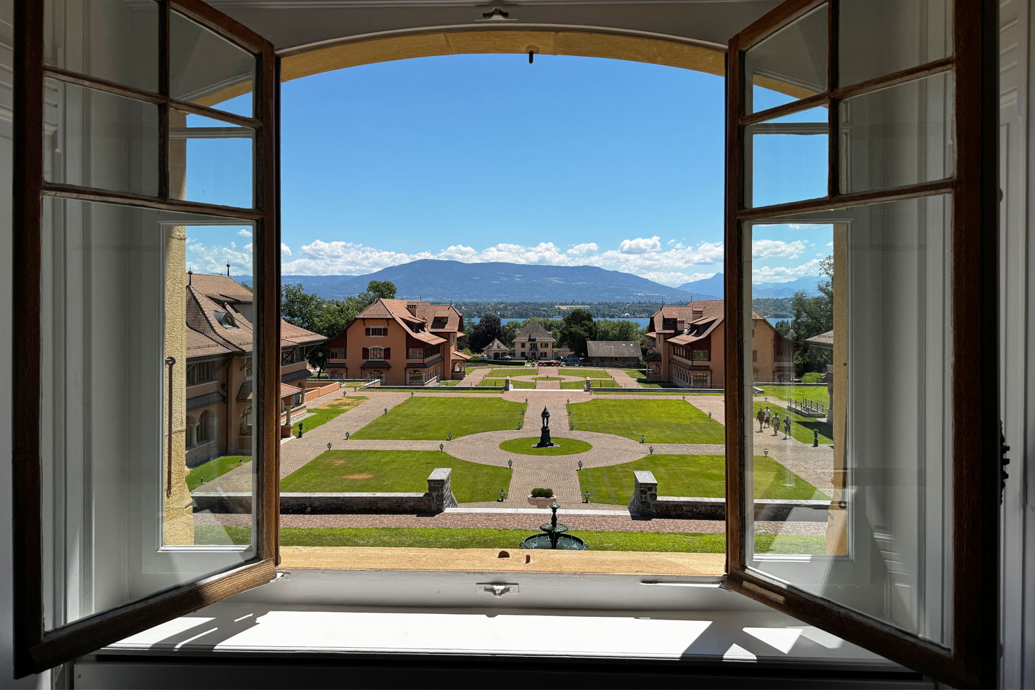 Blick aus dem Hauptgebäude in Watchland durch ein geöffnetes Fenster auf der Gelände von Watchland bis zum Genfer See
